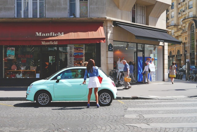 Woman getting into a car on a main street 